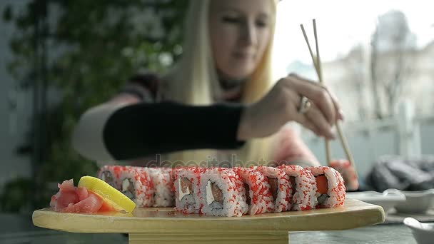 Fille manger sushi avec baguettes dans un japonais restaurant — Video