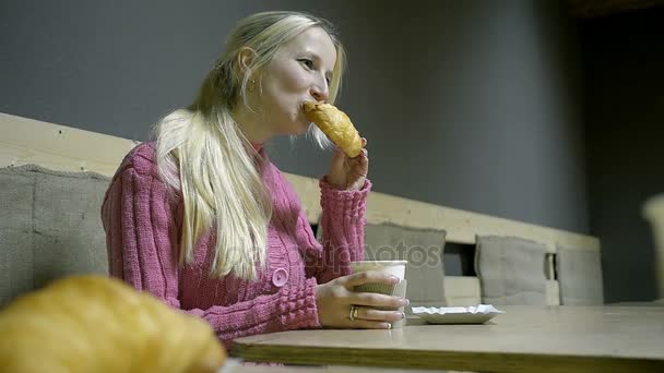 Junge Blondine frühstückt in einem Café und trinkt heißen Kaffee — Stockvideo