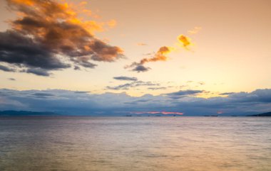Sahilde deniz ve ada manzaralı günbatımı