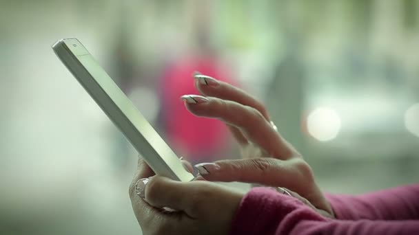 Mano femenina escribiendo un mensaje en un teléfono inteligente cerca de la ventana — Vídeo de stock