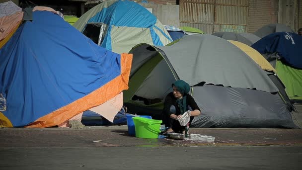 Athens 12. april: syrerin wäscht geschirr auf der straße in einem flüchtlingslager 12. april 2016 in athens. — Stockvideo