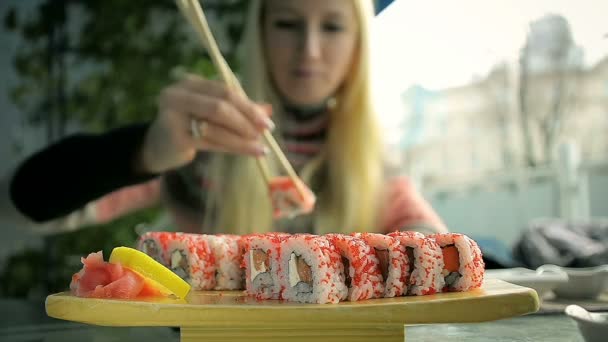 Närbild ung flicka äta Sushi med pinnar i en japansk restaurang — Stockvideo