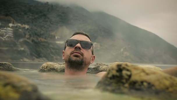 Joven Bespectacled toma un baño mineral caliente en el Resort — Vídeo de stock