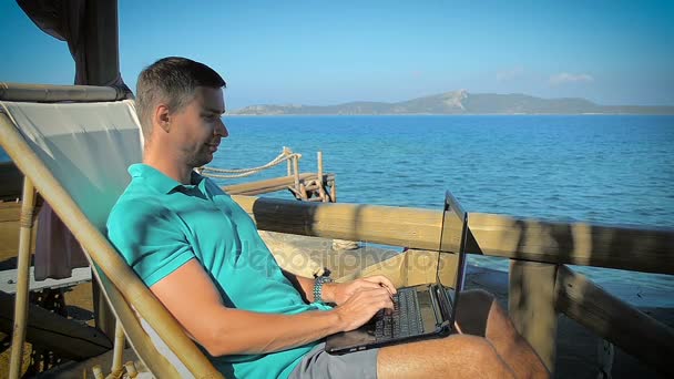 Людина за лист на ноутбуці на курорт на березі моря — стокове відео