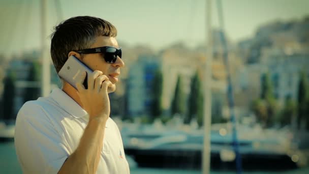 Man praten op de Smart-Phone op een rust in de jachthaven — Stockvideo