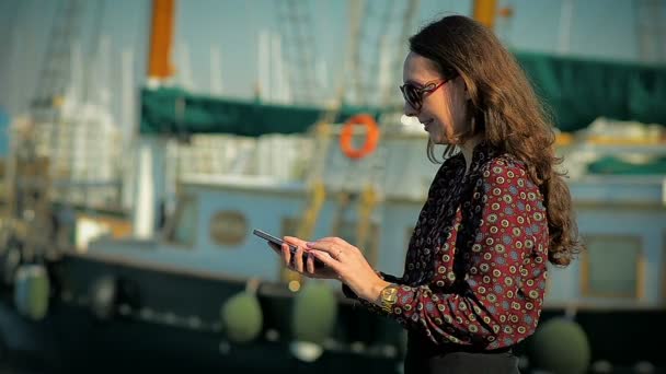 Fille communique dans les réseaux sociaux au téléphone dans une marina — Video