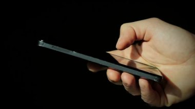 Yakın çekim erkek el siyah arka plan üzerine bir akıllı telefon kullanma