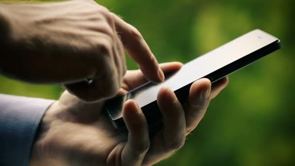 Primer plano de la mano masculina usando el teléfono inteligente al aire libre en el parque — Vídeo de stock