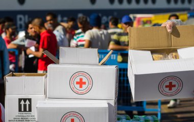 Yunan liman Suriyeli mülteciler bir arka plan üzerinde Kızıl Haç Uluslararası misyonun gıda ile tam kutuları