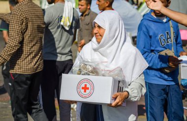 Elderly Syrian women received a box of food from the mission of the Red Cross in the Greek port clipart