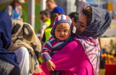Anne kucağında küçük bebeği Yunan limanda bir mülteci kampında tutar..
