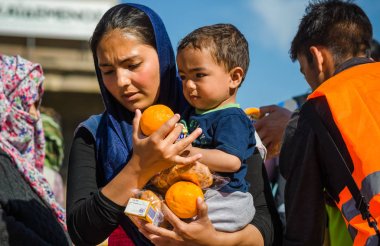 Anne oğlu ile Yunan limanda bir mülteci kampında hayırsever kuruluşlardan meyve almak