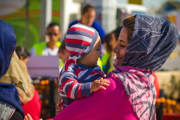 Mutlu Suriye anne kucağında küçük bebeği bir mülteci kampında tutar..