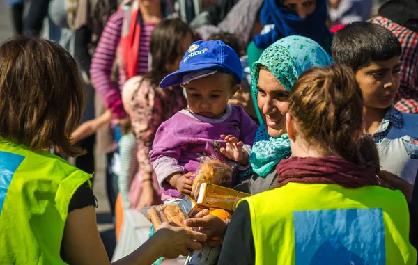Suriye anne ile küçük oğlu bir mülteci kampında hayırsever kuruluşlardan suyu ve meyve almak