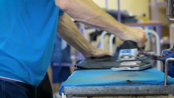 Zbliżenie, a pracownik prasowanie odzieży w fabryce włókienniczej — Wideo stockowe