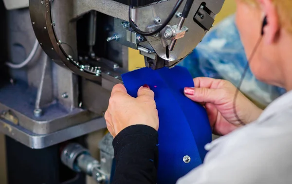 Worker at garment factory uses equipment on the production of clothing