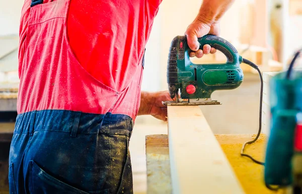 Bir işçi üniforma ve büyük ahşap tahta kesme ahşap mobilya fabrikası dükkanda giyen adam yakın çekim