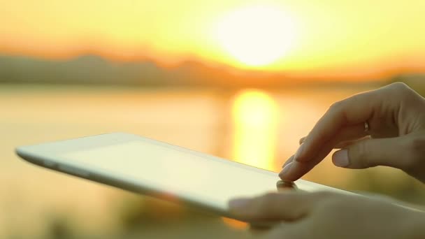 使用平板电脑在河边上，夕阳的特写女性手 — 图库视频影像