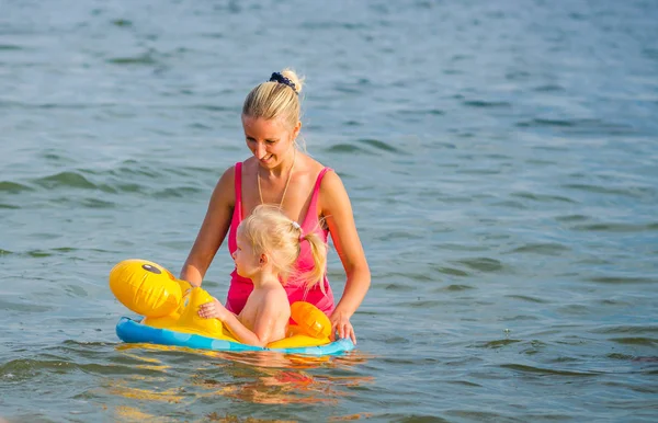 Τριών ετών κορίτσι κολυμπάει στη θάλασσα κάθισε στο δαχτυλίδι καουτσούκ με τη μητέρα της. — Φωτογραφία Αρχείου