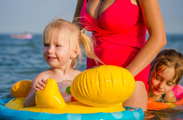 Крупный план маленькая девочка плавает в море со своей сестрой и матерью
.