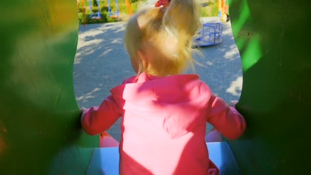 Movimiento lento: niña de tres años baja del tobogán en el patio de recreo. Vista desde arriba . — Vídeos de Stock