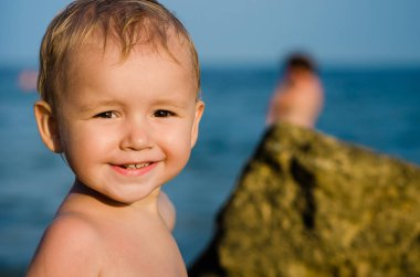Deniz kıyısı üstünde iki yaşındaki bir oğlan Close-Up kameraya benziyor.