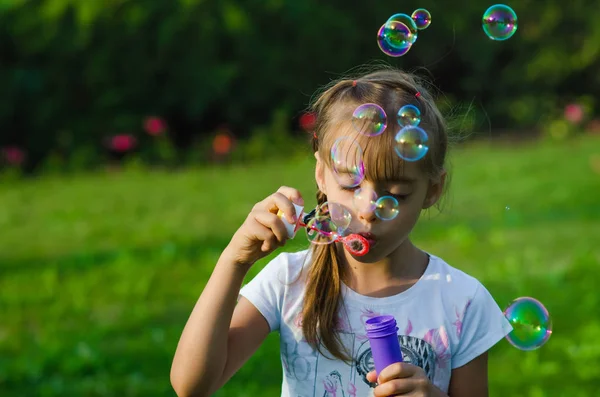 Yakın çekim altı yaşındaki bir kız balonu açık parkta üfleme.