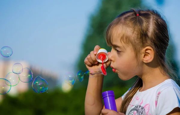 Yakın çekim altı yaşındaki bir kız sabun köpüğü açık parkta üfleme. — Stok fotoğraf