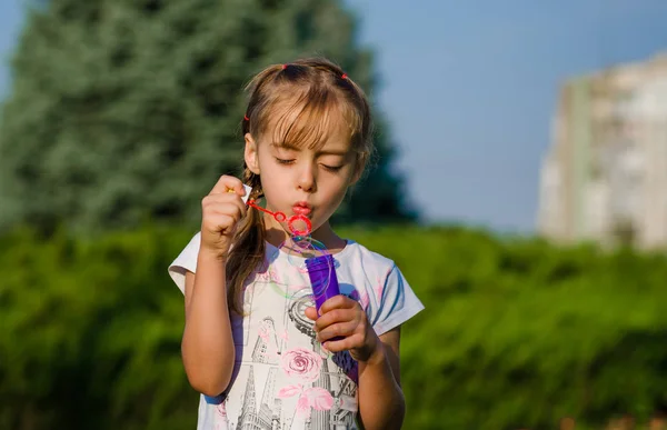 Γκρο πλαν ένα κοριτσάκι έξι ετών φυσώντας σαπούνι-φυσαλίδα στο πάρκο. — Φωτογραφία Αρχείου