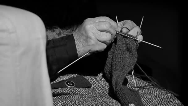Крупный план бабушкиного вязания теплых шерстяных носков на диване в монохромном стиле — стоковое видео