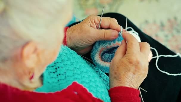 Närbild av en mormor hand sticka varma strumpor för hennes barnbarn som sitter på soffan. — Stockvideo
