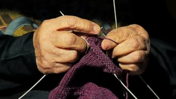 Nahaufnahme einer alten Großmutter, die warme Socken für ihre Enkel strickt. — Stockvideo