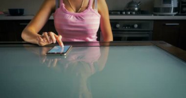 Dolly bir erkek arkadaşlarıyla evde mutfakta akıllı telefon üzerinde bir ileti yazar.