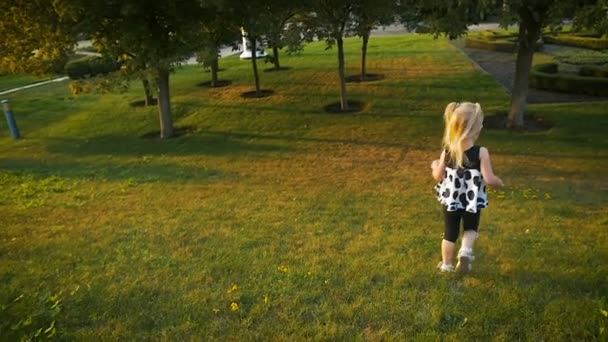 Movimiento lento: niña de tres años corriendo en el parque de verano en la hierba verde . — Vídeos de Stock