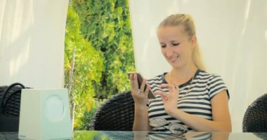 Genç güzel sarışın karşılık gelen yaz kafede akıllı telefon üzerinde arkadaşlarınızla.