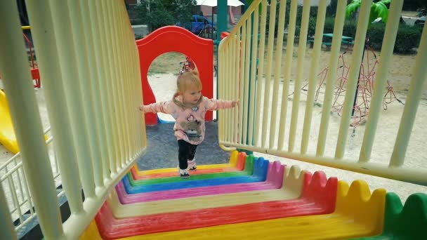 Movimiento lento: niña de tres años sube lentamente en el tobogán en el patio de recreo . — Vídeos de Stock