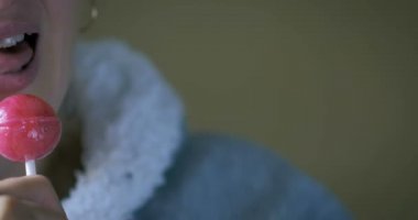 Dolly yakın çekim yemek genç bir kız ve bir tatlı şeker bir çubuğa yalıyor.