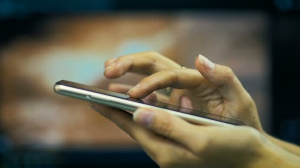 SLOW MOTION : jeune fille parcourt les pages sur Internet sur smart-phone sur un fond d'écran d'ordinateur portable .