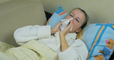 Yakın çekim bir Beyaz önlük içindeki bir hasta genç kız hapşırma ve burnunu kanepeye yalan mendil.