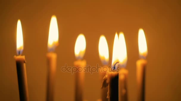 Close-up de um monte de belas velas de cera queimando. Fundo amarelo . — Vídeo de Stock