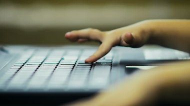 Ağır çekim: Yakın çekim üç yıllık bir kız evde laptop klavye üzerinde metni yazdırır.