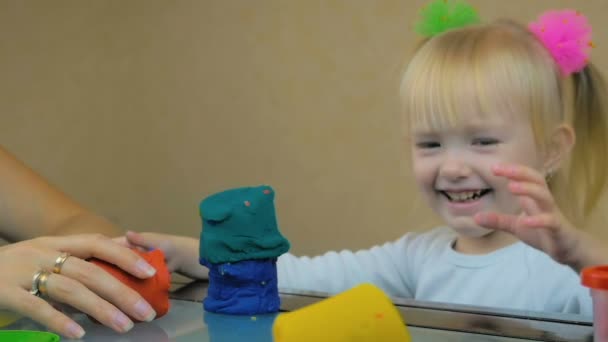 Крупним планом мама і її трирічна дочка будують вежу з пластиліну за столом вдома . — стокове відео