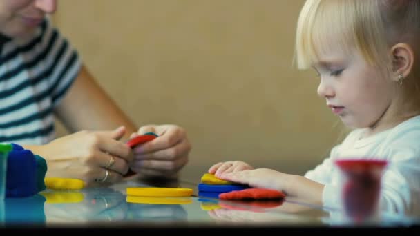 LOW MOTION: close-up uma mãe ensina sua filha de três anos de idade a esculpir estatuetas de plasticina . — Vídeo de Stock