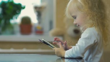 Ağır çekim: yakın çekim üç-yıl-yaşlı saat karikatürler bir smartphone ve kamera göz küçük bir kız.