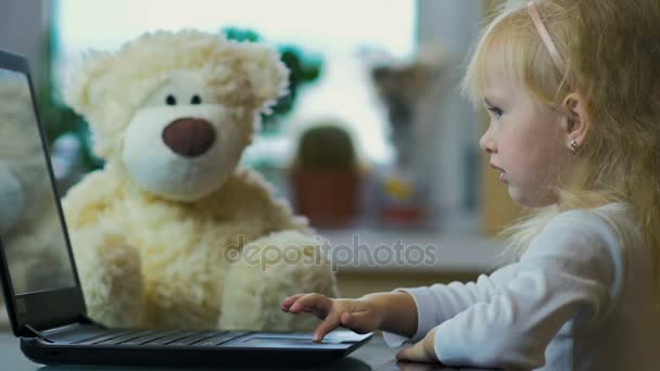 Zeitlupe: Dreijähriges Mädchen zeigt Karikaturen auf Laptop und schaut zu Hause am Bildschirm zu. — Stockvideo