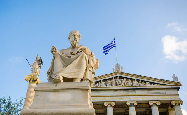 Statue of the great Greek philosopher Plato on background classical columns and the Greek flag. 