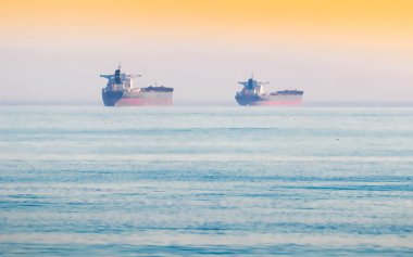 İki büyük kargo gemisi gün batımında üretilmiş mallarla denize açılır..