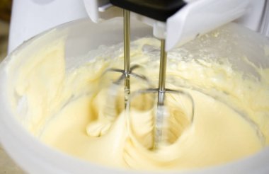 Evdeki mutfakta lezzetli ev yapımı pişirmeler için krema hazırlayan bir mikserin yakın çekimi..