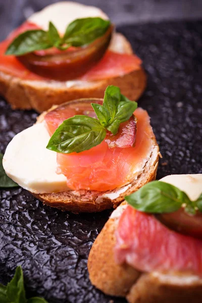 Crostini com salmão, mussarela, tomate e manjericão — Fotografia de Stock
