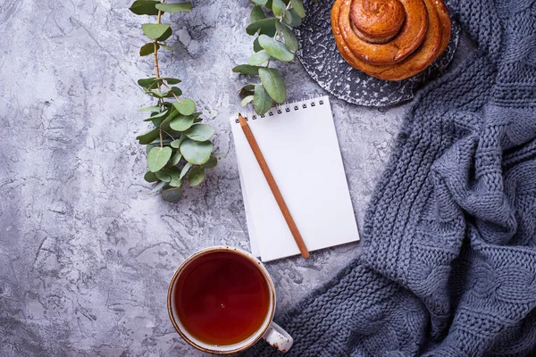 Espacio de trabajo femenino con bollo, taza de té y cuaderno — Foto de Stock